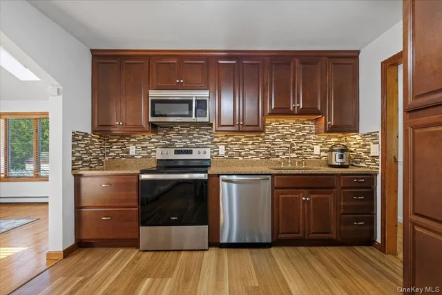 a kitchen with stainless steel appliances kitchen island granite countertop wooden cabinets and a sink