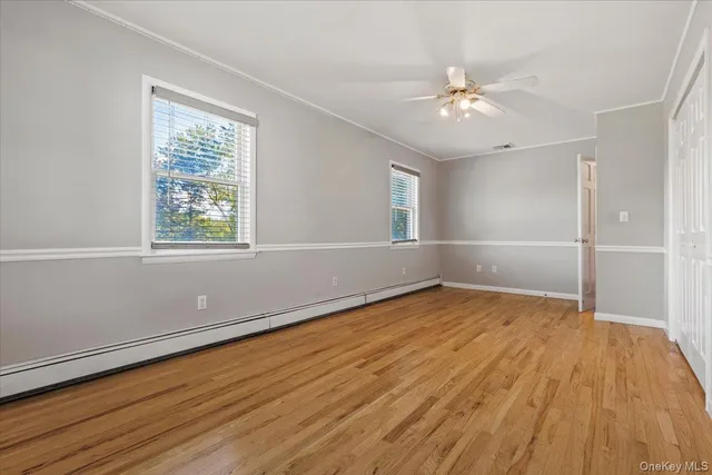 an empty room with wooden floor fan and windows