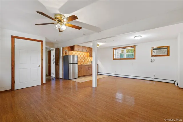 a view of an empty room with wooden floor and a ceiling fan