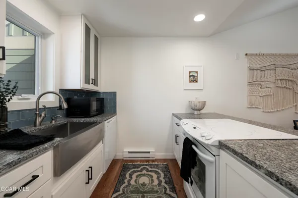 a kitchen with a sink and a stove top oven with wooden floor