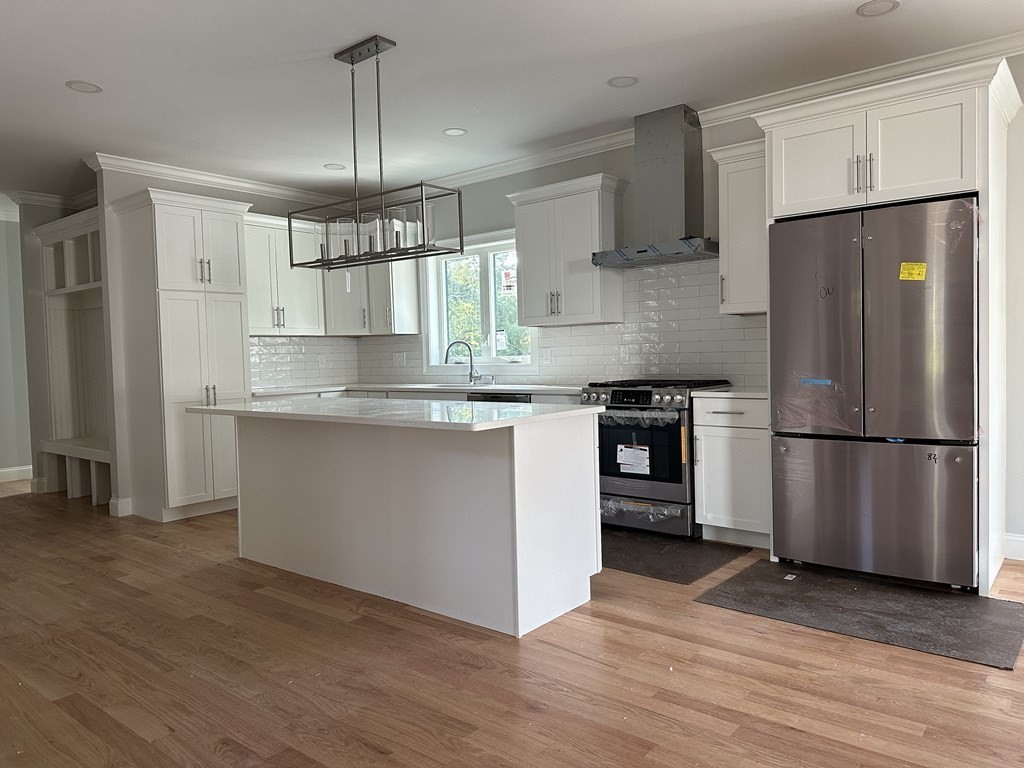 225 High Street Canton, MA 02021 - Photo 3 of 22 a kitchen with kitchen island granite countertop a refrigerator a sink dishwasher a stove and white cabinets with wooden floor