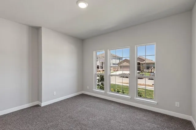 a view of an empty room with wooden floor and a kitchen