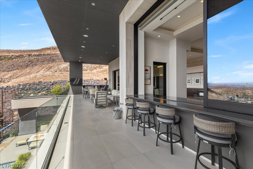 657 Ridgestone Rim Court Henderson, NV 89012 - Photo 44 of 97 Floor-to-ceiling sliding glass doors seamlessly connect the indoor bar to a spacious tiled balcony.