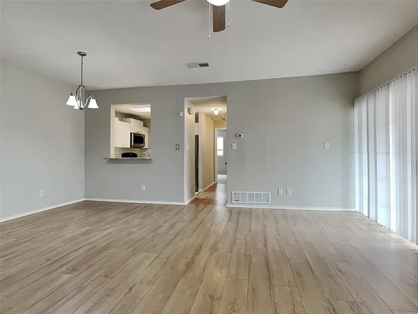 an empty room with wooden floor cabinet and windows