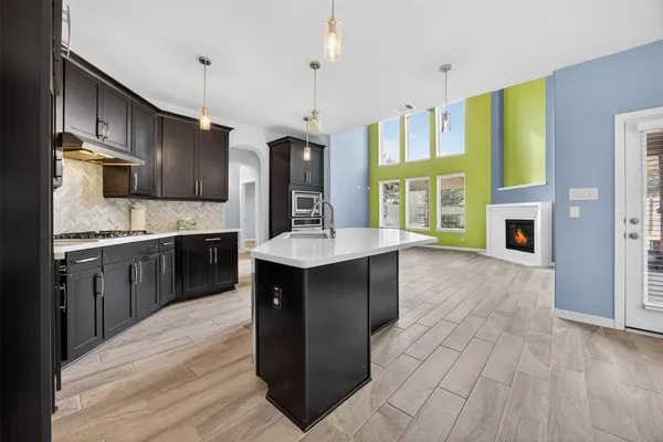a kitchen with stainless steel appliances granite countertop a refrigerator a sink dishwasher a stove and a dining table with wooden floor