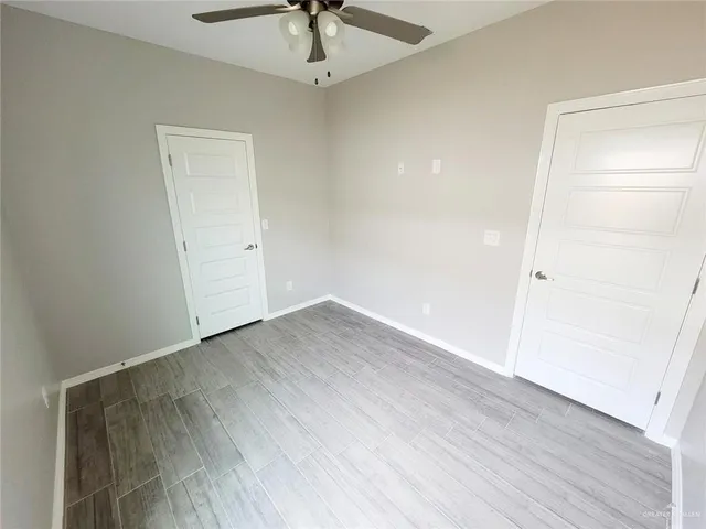 an empty room with wooden floor and ceiling fan