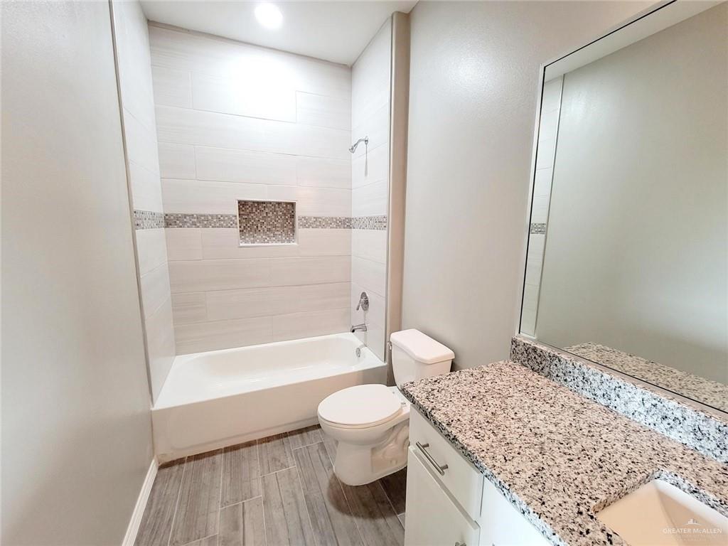 2109 Davenport Street, Unit 1 Weslaco, TX 78596 - Photo 8 of 13 a bathroom with a granite countertop sink toilet a mirror and bathtub