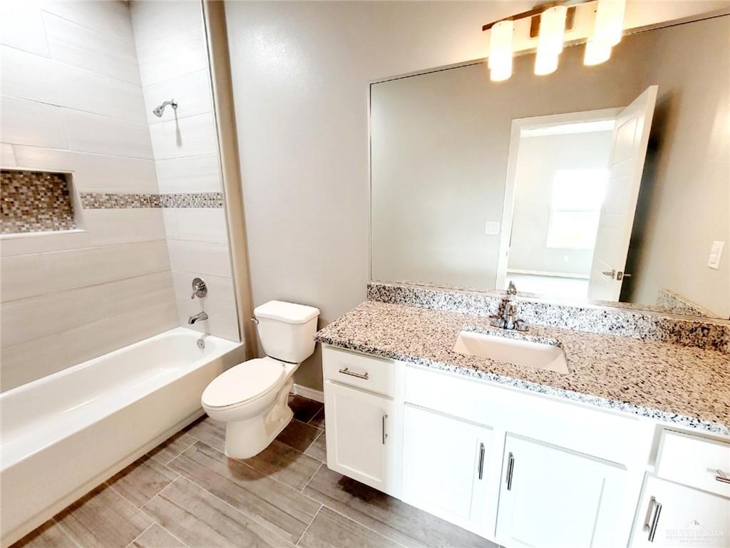 2109 Davenport Street, Unit 1 Weslaco, TX 78596 - Photo 9 of 13 a bathroom with a granite countertop toilet a sink and a bathtub