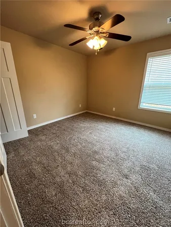 an empty room with a chandelier fan and windows