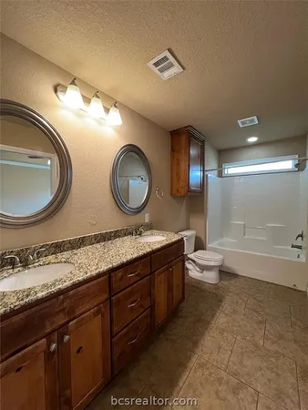 a bathroom with a granite countertop toilet a sink and a mirror