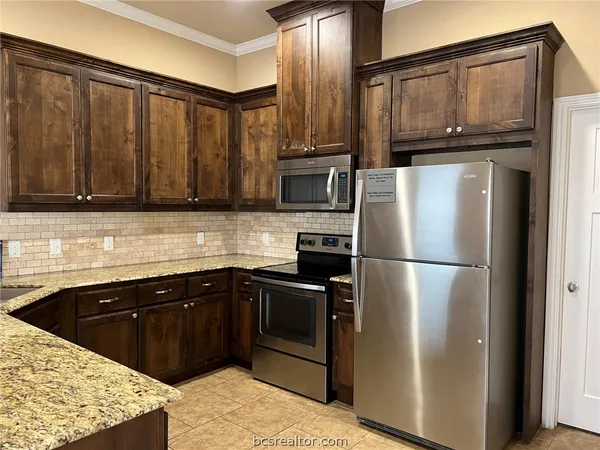 a kitchen with stainless steel appliances granite countertop a refrigerator a stove a sink and dishwasher