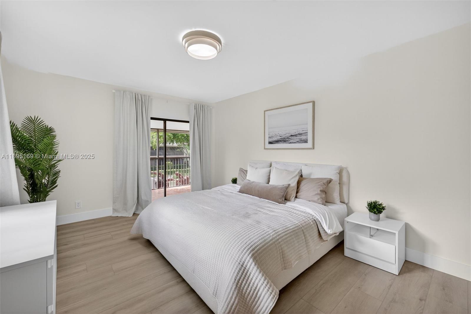 261 Deer Creek Boulevard, Unit 1205 Deerfield Beach, FL 33442 - Photo 11 of 38 a large bed sitting in a bedroom next to a window and a potted plant