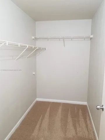 an empty room with closet and a chandelier fan