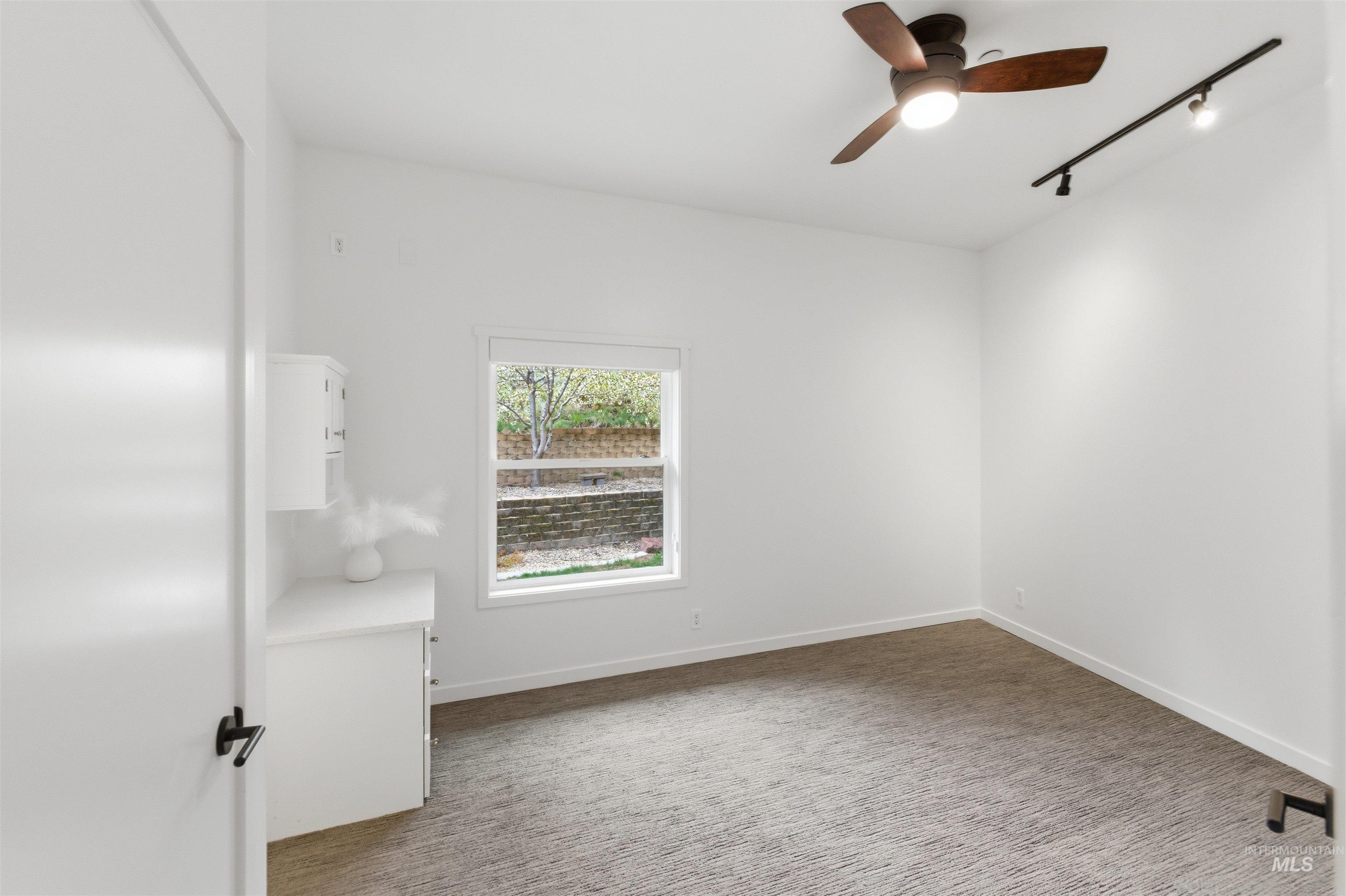 4275 36th Street Boise, ID 83703 - Photo 12 of 50 Spare room featuring rail lighting, dark carpet, and a ceiling fan
