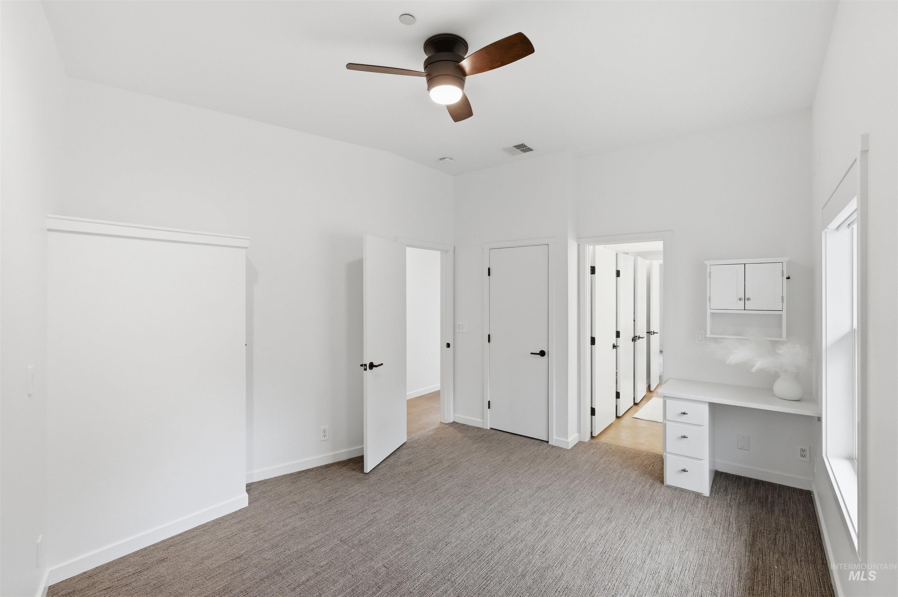 4275 36th Street Boise, ID 83703 - Photo 13 of 50 Unfurnished bedroom with ceiling fan, built in desk, and light carpet