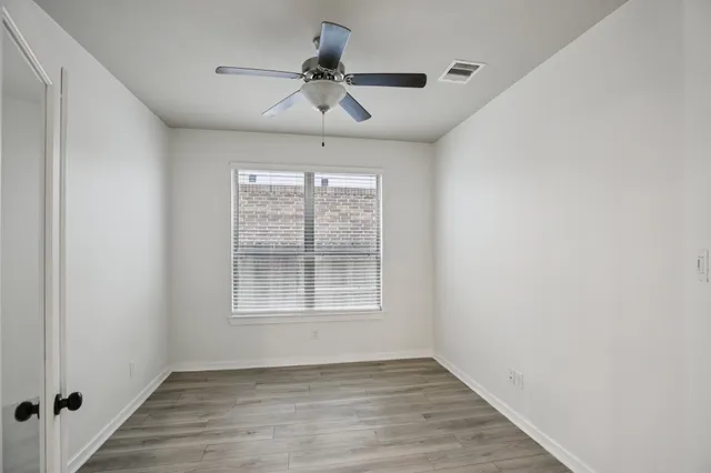a view of an empty room with wooden floor and a window