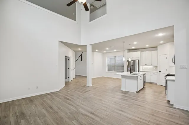 a view of kitchen with stainless steel appliances refrigerator stove and wooden floor