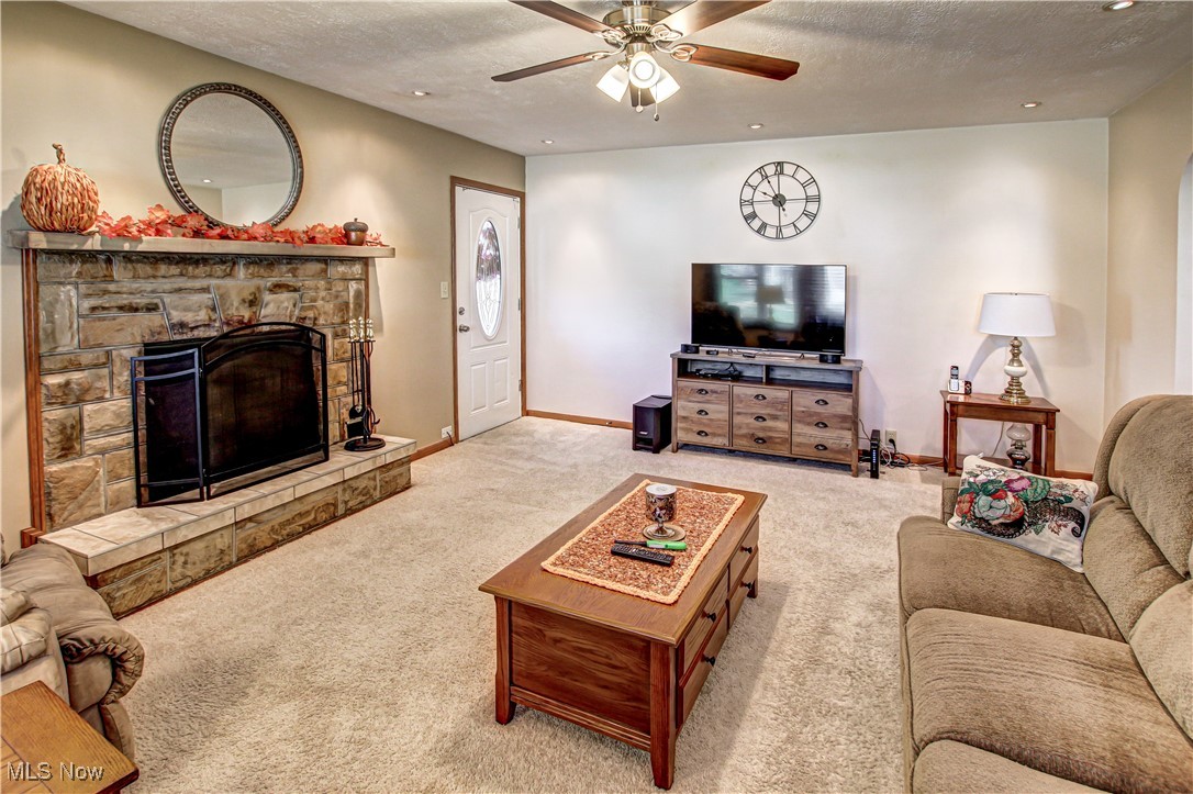 4234 Grafton Road Brunswick, OH 44212 - Photo 10 of 40 Living room featuring a textured ceiling, a stone fireplace, light colored carpet, and ceiling fan