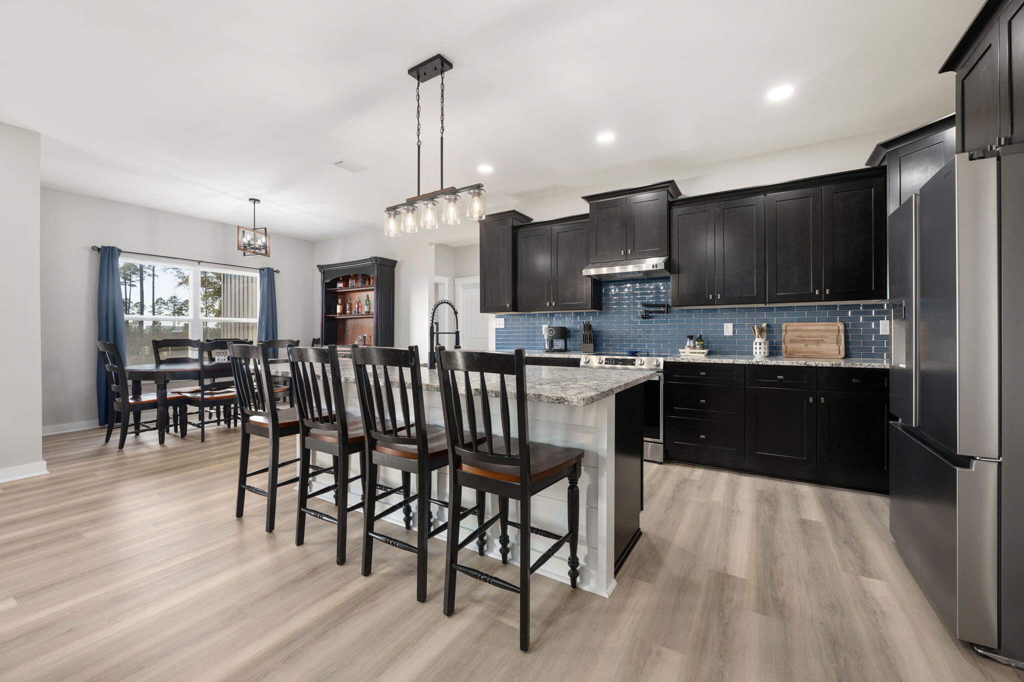 6150 Sherman Kennedy Road Baker, FL 32531 - Photo 8 of 43 a kitchen with stainless steel appliances kitchen island granite countertop a table chairs sink and cabinets