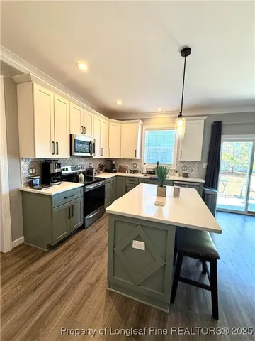 a kitchen with kitchen island a stove a table and chairs in it
