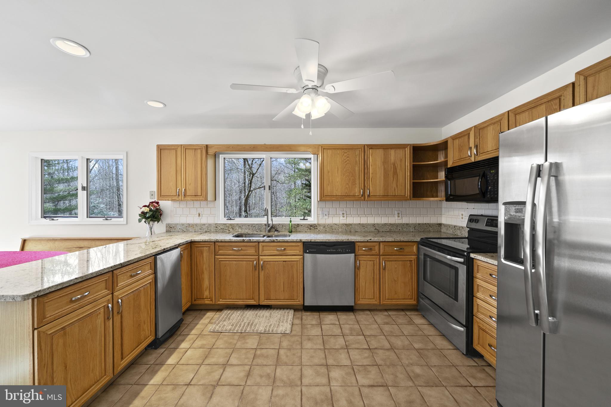 6251 Stephen Reid Road Huntingtown, MD 20639 - Photo 19 of 46 a large kitchen with stainless steel appliances granite countertop a sink and dishwasher a refrigerator with wooden cabinets
