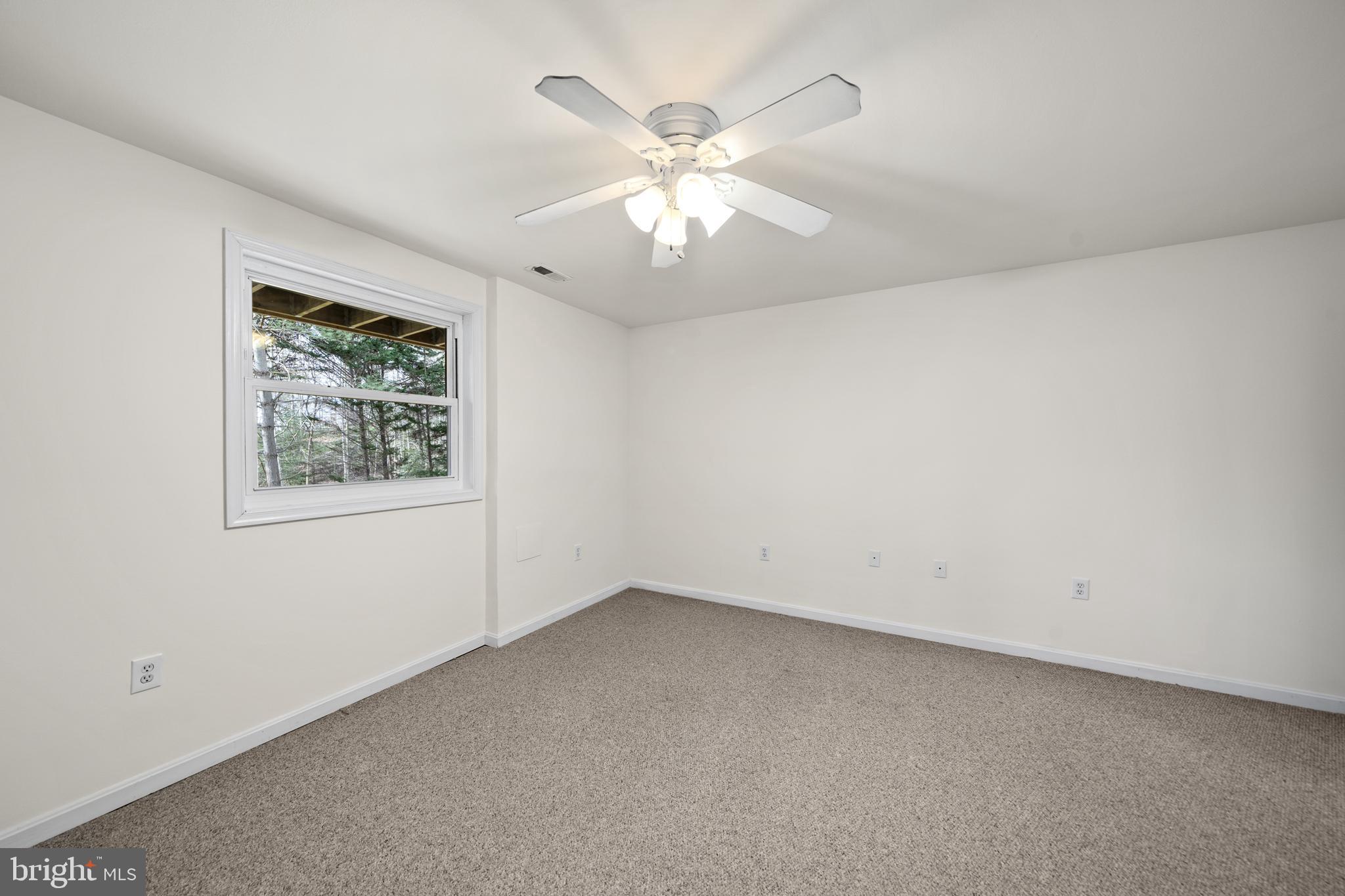 6251 Stephen Reid Road Huntingtown, MD 20639 - Photo 32 of 46 an empty room with a window and a ceiling fan