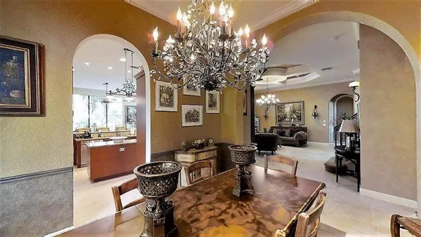 a dining room with wooden floor a chandelier a wooden table and chairs