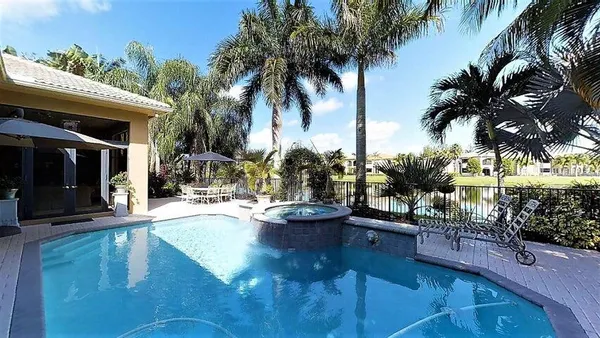 a view of a swimming pool with lounge chair and palm trees