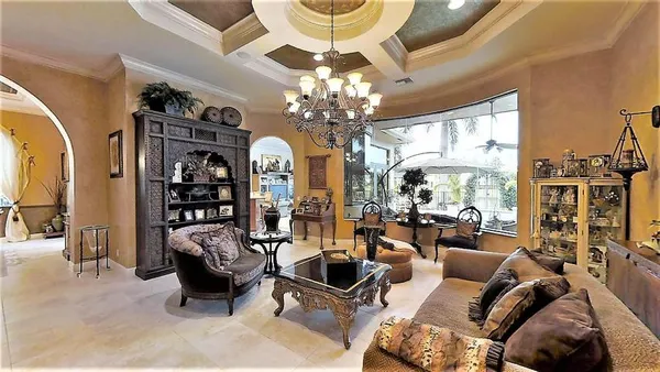 a living room with furniture a chandelier and a large mirror