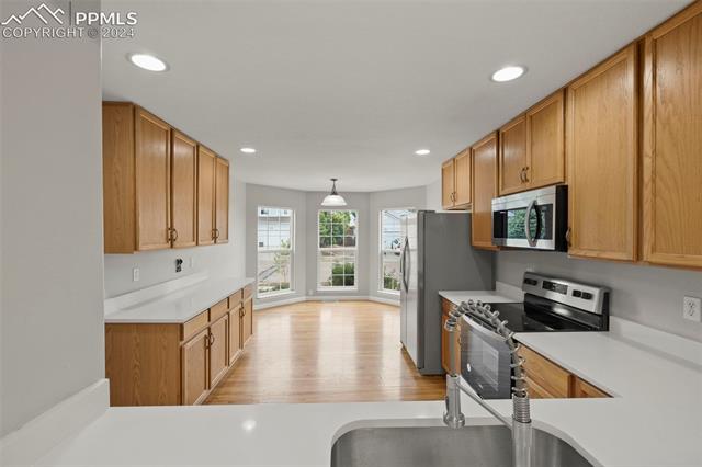 6725 Akron Road Colorado Springs, CO 80923 - Photo 10 of 50 Kitchen with stainless steel appliances, light hardwood / wood-style floors, and decorative light fixtures
