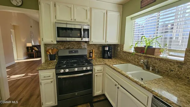 a kitchen with granite countertop a sink stove and cabinets