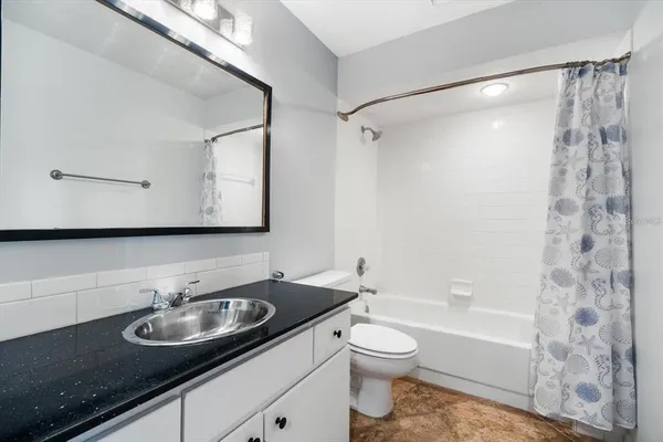 a bathroom with a granite countertop sink a toilet and shower