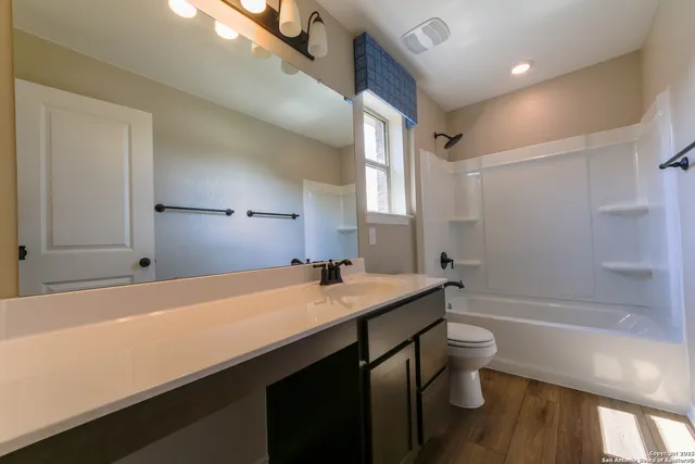 a spacious bathroom with a granite countertop sink a toilet a mirror and shower
