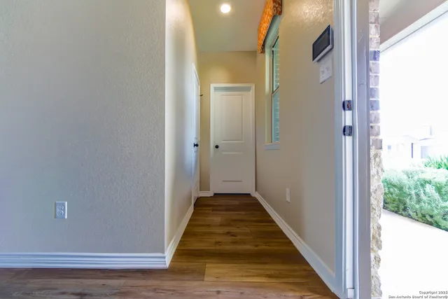 a view of a hallway with wooden floor and a bathroom