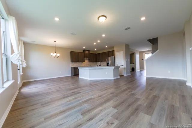 a view of a big room with wooden floor and a kitchen