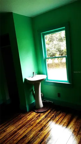 a view of an empty room with window and wooden floor