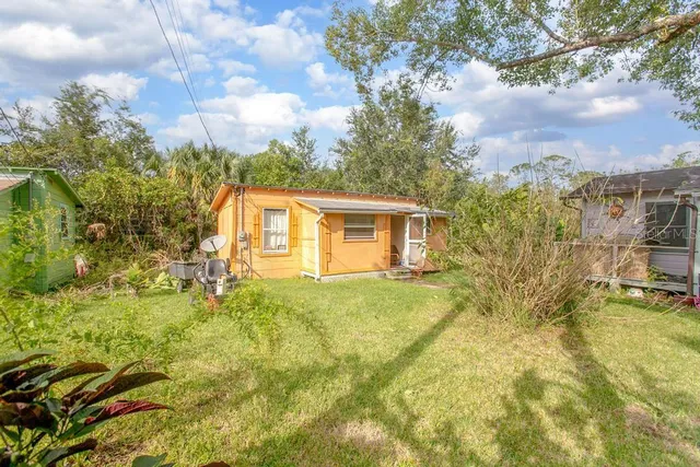 a view of a backyard with plants and large trees