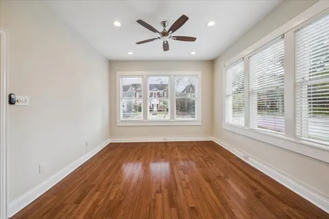 a view of empty room with wooden floor and fan