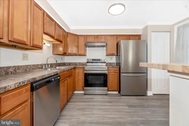 a kitchen with granite countertop a stove top oven and refrigerator
