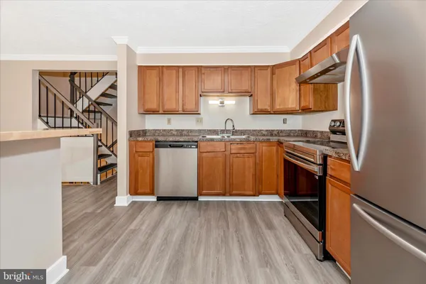 a kitchen with stainless steel appliances granite countertop wooden floors and wooden cabinets