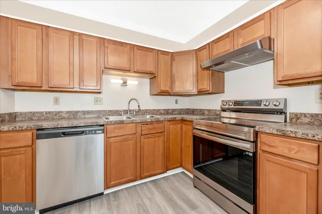 a kitchen with granite countertop wooden cabinets stainless steel appliances and a counter space