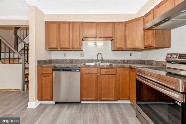 a kitchen with granite countertop wooden cabinets a sink and dishwasher
