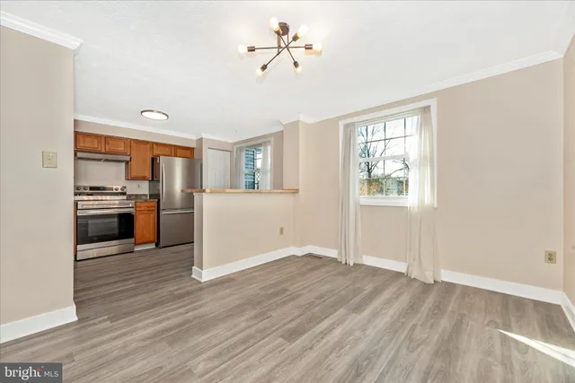 a view of a kitchen and an empty room with wooden floor and a kitchen