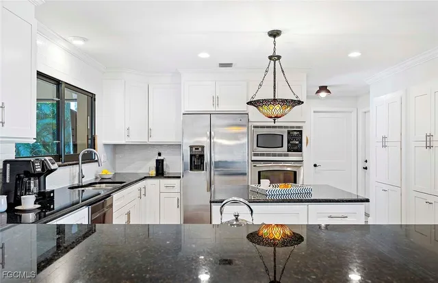 a kitchen that has a lot of cabinets in it and stainless steel appliances