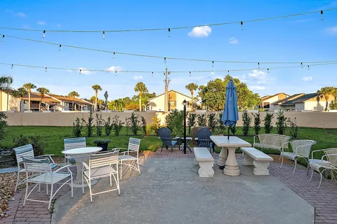 a view of a patio with dining table and chairs with plants and a grill