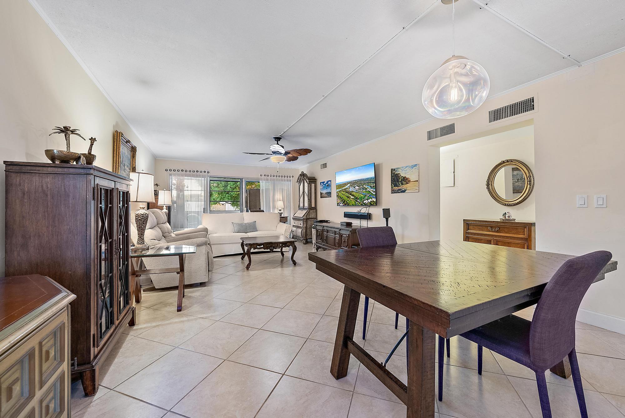 1561 Northeast 12th Terrace, Unit C14 Jensen Beach, FL 34957 - Photo 7 of 38 a view of a dining room and livingroom view with furniture a rug and a clock
