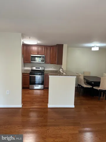a kitchen with stainless steel appliances a sink a stove a microwave and wooden floors