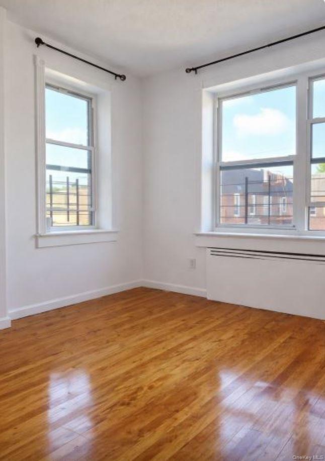 33-16 82nd Street, Unit 6D Queens, NY 11372 - Photo 11 of 16 Spare room featuring light wood-type flooring, healthy amount of natural light, and radiator heating unit