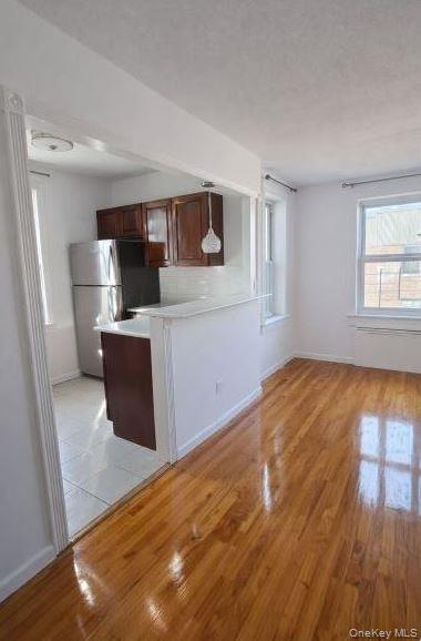 33-16 82nd Street, Unit 6D Queens, NY 11372 - Photo 2 of 16 Kitchen with light wood finished floors, freestanding refrigerator, light countertops, and decorative backsplash