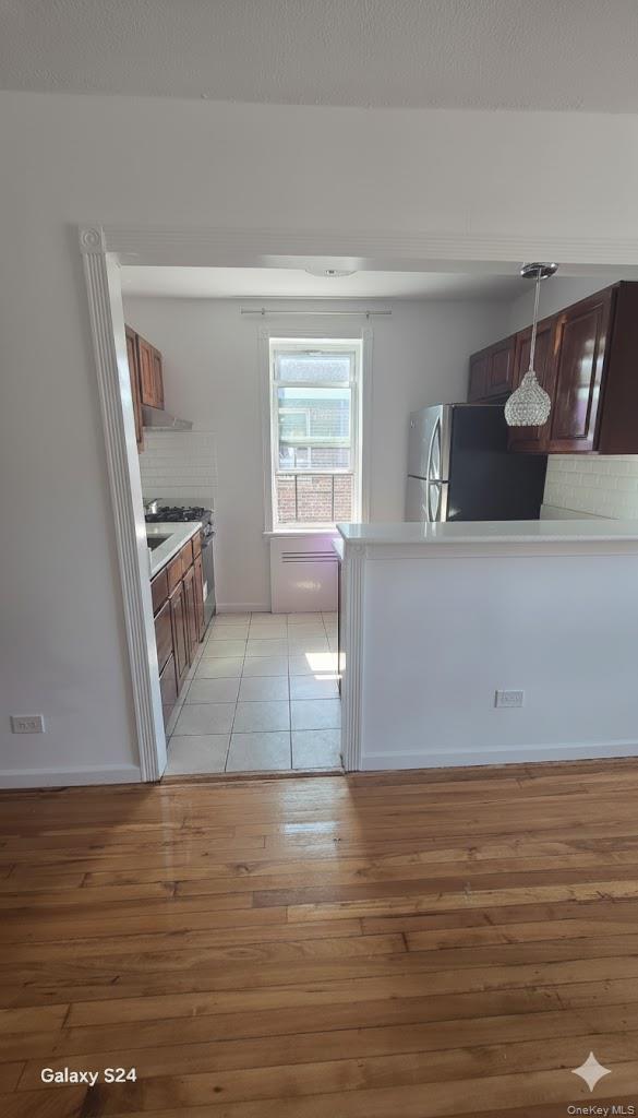 33-16 82nd Street, Unit 6D Queens, NY 11372 - Photo 10 of 16 Kitchen with decorative backsplash, light countertops, freestanding refrigerator, a peninsula, and light wood-style flooring